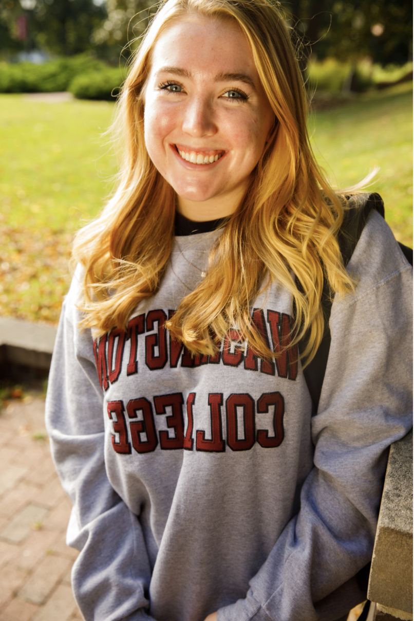 哈雷, smiling and wearing a grey hoodie with "Washington College" in red lettering. 